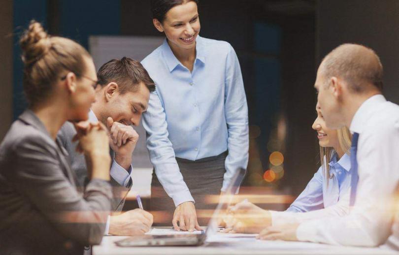 Smiling female boss talking to business team