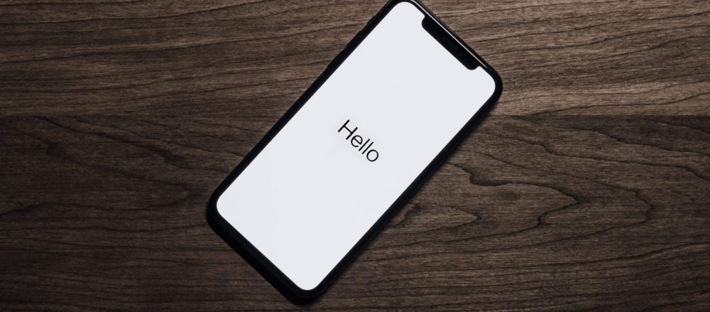 A cell phone on the table with the text "hello" on the screen