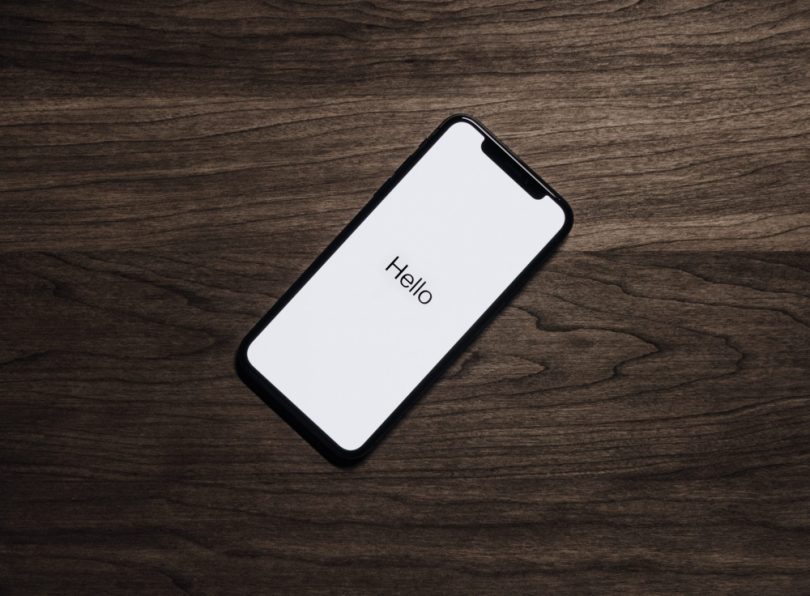 A cell phone on the table with the text "hello" on the screen
