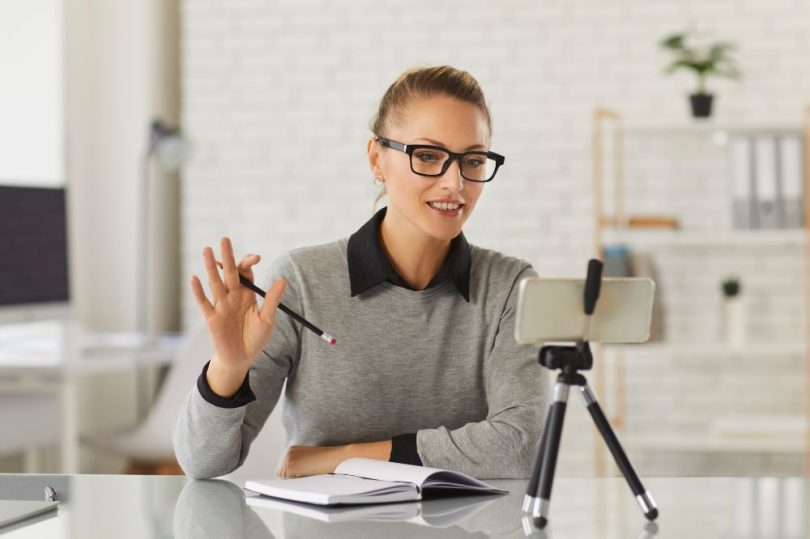 A woman delivering a lecture to a webcam.