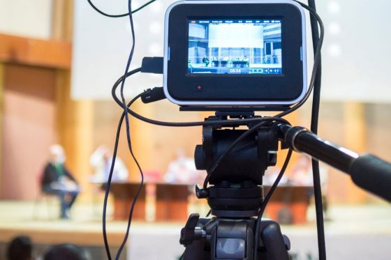 A video camera live streams an in-person event session.