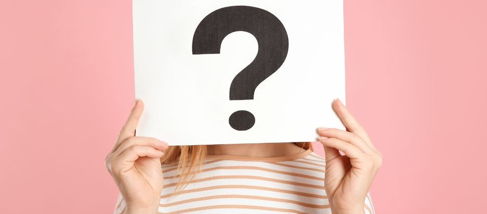 Woman holding a question mark in front of her face