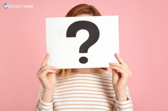 Woman holding a question mark in front of her face