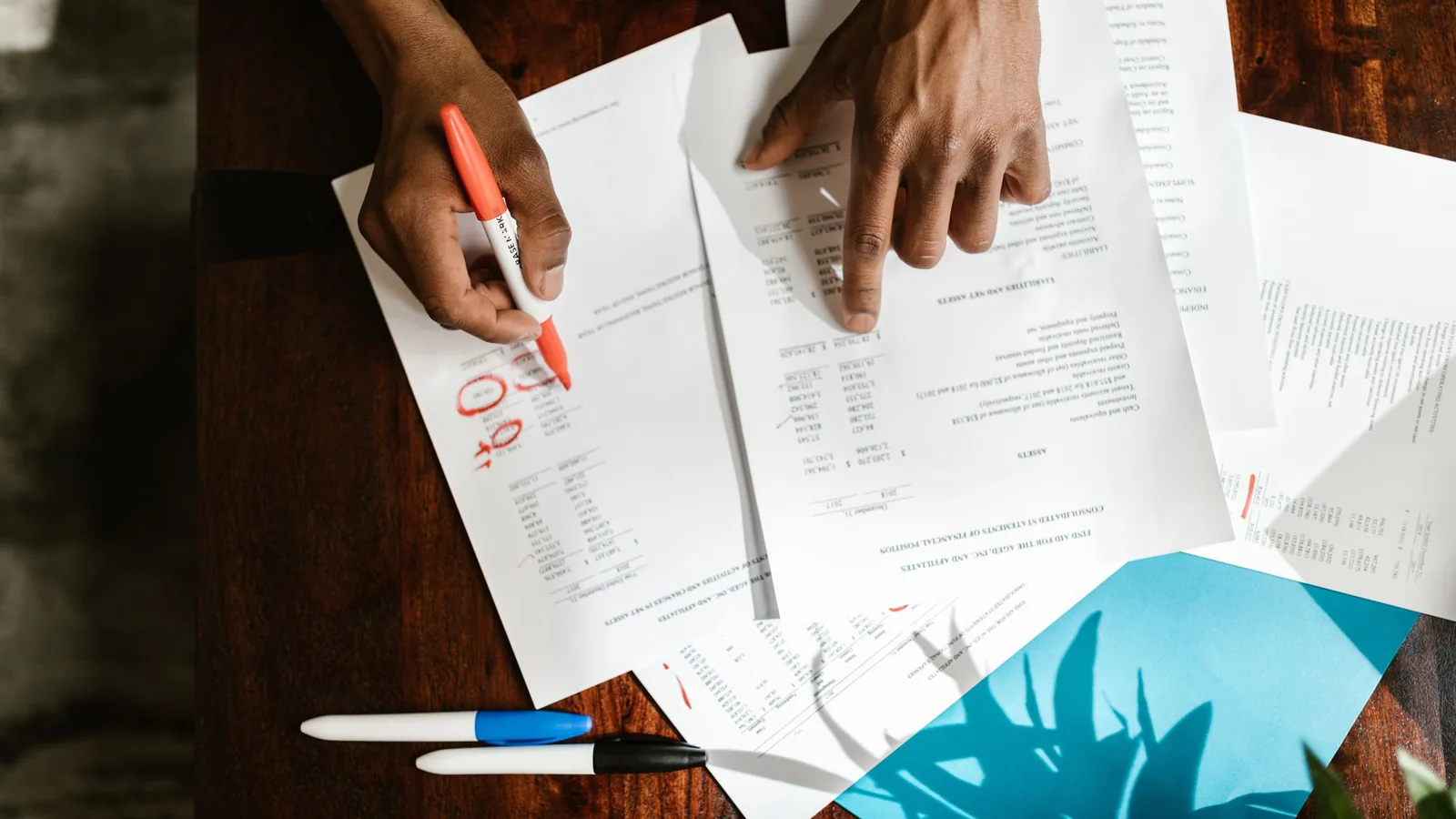 A hand reviews a document with a pen in warm natural light.