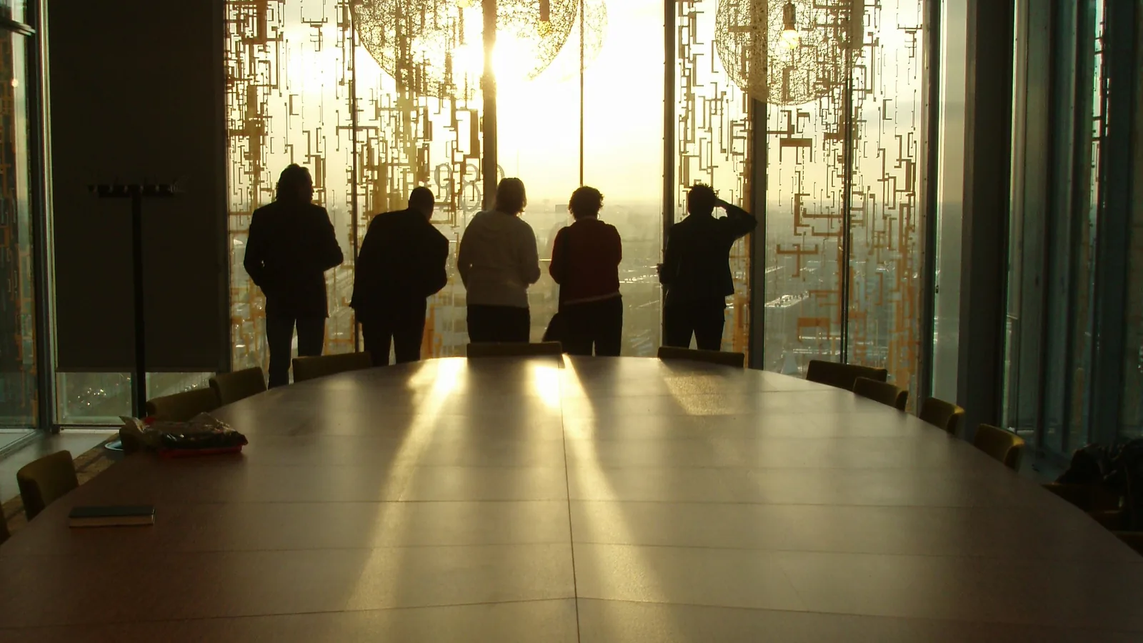 People gather in a warm room beside large glass doors.