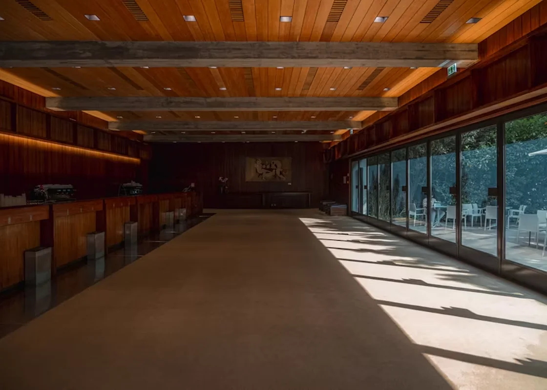 Sunlit wood interior with glass walls and a clear route forward.