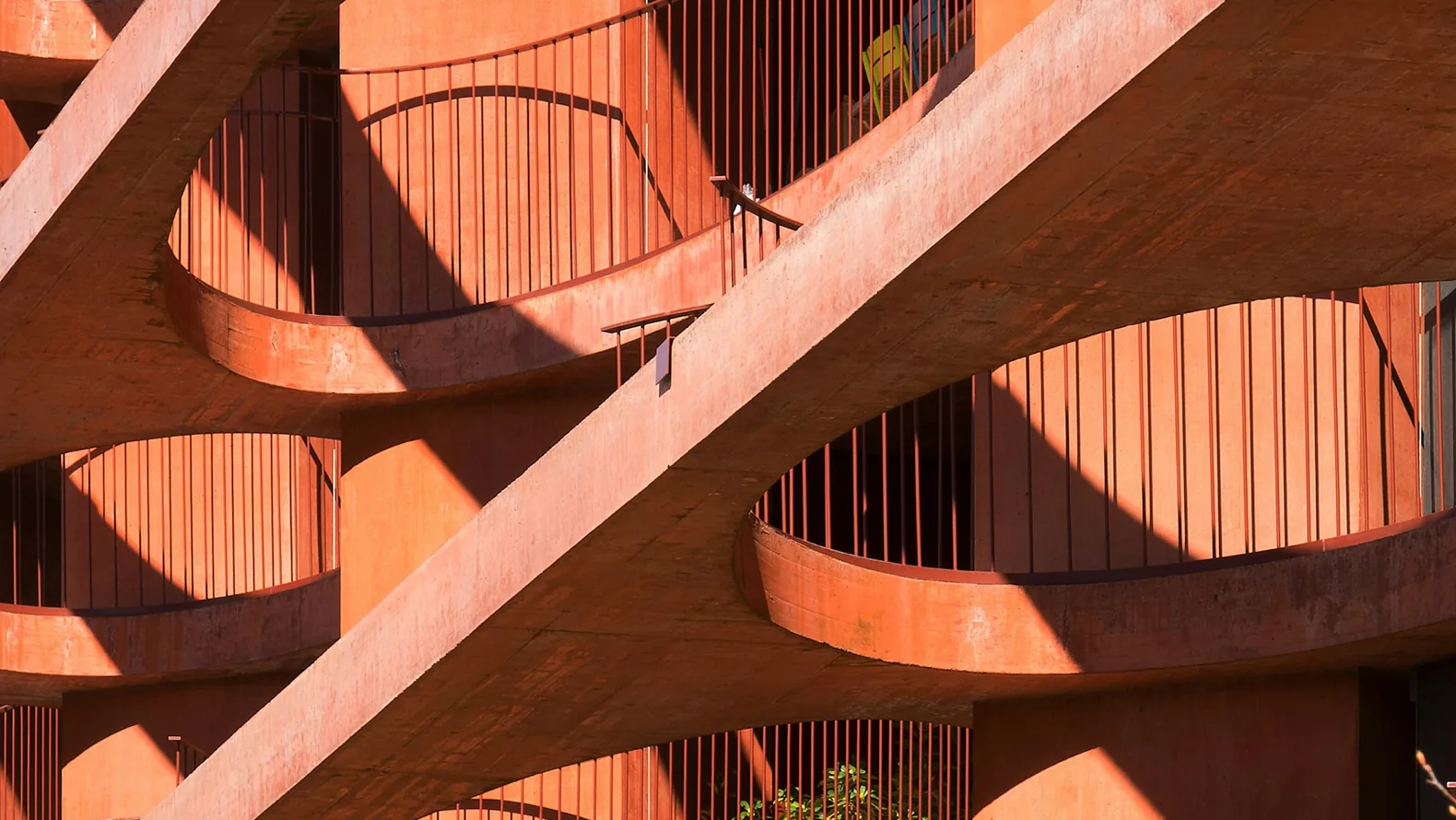 Sunlit terracotta balconies connected by structural supports.