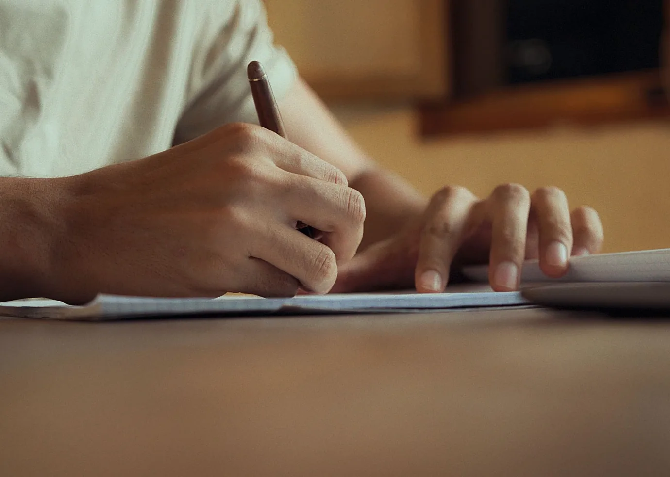 Hands recording working knowledge in a notebook in warm natural light.