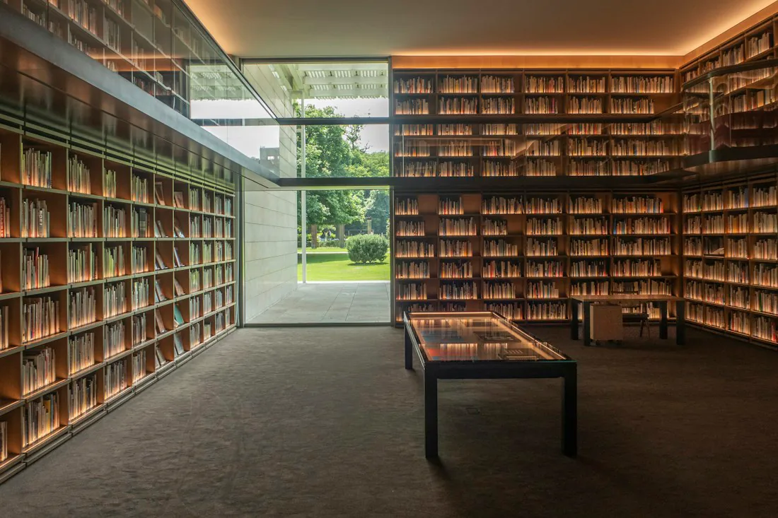 Warmly lit library shelves opening onto a green garden.