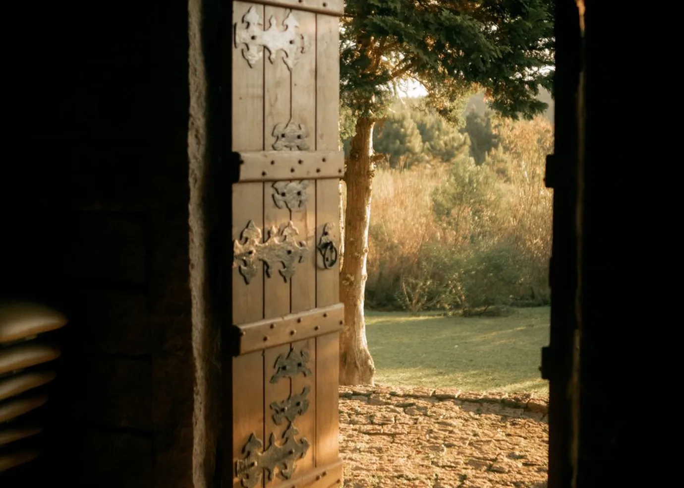 An open wooden doorway leading into a sunlit garden.